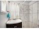 Bathroom features a stylish vanity with a vessel sink and white and marble textured shower tile at 150 N 7Th Ave, Brighton, CO 80601