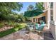 Backyard patio area with a green umbrella and table with seating with a manicured lawn and surrounding trees at 7120 Forest Ridge Cir, Castle Pines, CO 80108