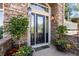 Elegant front door with decorative glass, stone accents, and lush landscaping create inviting curb appeal at 7120 Forest Ridge Cir, Castle Pines, CO 80108