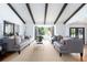 Open-concept living room with exposed beams, neutral decor, and abundant natural light at 3843 S Quince St, Denver, CO 80237
