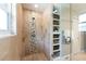 Tiled shower with geometric accent tile, built in shelving, and glass door at 3843 S Quince St, Denver, CO 80237