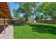 Well-maintained backyard with a verdant lawn, mature trees, and a covered patio, offering a serene outdoor space at 1560 Simms St, Lakewood, CO 80215
