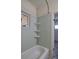 Bathroom highlighting the bathtub with shower head, light-blue tiling, window, and shelving at 1560 Simms St, Lakewood, CO 80215