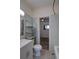 Bathroom with light-blue tiling, toilet, sink, shelving, and a doorway to the carpeted bedroom at 1560 Simms St, Lakewood, CO 80215