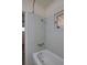 Bathroom showing a bathtub, shower head, light-blue tiling, and window with a view of the outside at 1560 Simms St, Lakewood, CO 80215