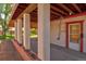 View of the covered patio with brick accents, supporting columns and a door leading to additional space at 1560 Simms St, Lakewood, CO 80215