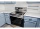 Modern stainless steel oven/stove in kitchen with white countertops and blue cabinets at 551 Snowy Owl Pl, Highlands Ranch, CO 80126