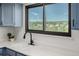 Sunlit kitchen sink under window with black fixtures and blue cabinets at 551 Snowy Owl Pl, Highlands Ranch, CO 80126
