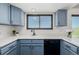 A bright kitchen features blue cabinets, white countertops, black hardware and trim, with a view out the window at 551 Snowy Owl Pl, Highlands Ranch, CO 80126