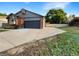 Charming single-Gathering home featuring a brick facade, gray siding, manicured lawn, and a convenient two-car garage at 12375 Ivy Pl, Brighton, CO 80602