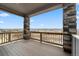 Spacious covered deck with stone columns, wood railing, and expansive scenic views at 1995 Wingfeather Ln, Castle Rock, CO 80108