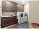 Laundry room featuring a sink, dark wood cabinetry, modern washer and dryer, and gray tile floors at 1995 Wingfeather Ln, Castle Rock, CO 80108