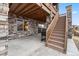 Covered outdoor patio featuring stone columns, a grill, and access to stairs at 1995 Wingfeather Ln, Castle Rock, CO 80108