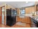 Kitchen features wood cabinets, a farmhouse sink, and black appliances at 2311 W 46Th Ave, Denver, CO 80211