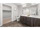 Bathroom featuring dual sinks, modern fixtures, and wood cabinets, with an adjacent walk-in closet at 20 Wilcox St # 318, Castle Rock, CO 80104