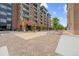 Modern apartment building with pedestrian plaza, outdoor seating, and trees at 20 Wilcox St # 318, Castle Rock, CO 80104