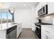 Modern kitchen featuring stainless steel appliances, white cabinetry, and a large window with a view at 126 S Vandriver Way, Aurora, CO 80018