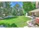 Beautiful backyard with lush green lawn, mature trees, a stone water feature, and a cozy covered patio at 6716 W Rowland Ave, Littleton, CO 80128