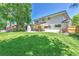 Expansive backyard featuring a large lawn, mature tree, and covered patio with an outdoor fireplace at 6716 W Rowland Ave, Littleton, CO 80128