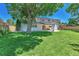 Spacious backyard with lush lawn, mature trees, white brick exterior, covered patio and outdoor fireplace at 6716 W Rowland Ave, Littleton, CO 80128