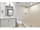 Bright bathroom featuring a walk-in tiled shower with gold hardware and a sleek vanity with white cabinetry at 6716 W Rowland Ave, Littleton, CO 80128