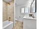 Bright bathroom featuring tiled shower/tub combo with gold hardware and a single sink vanity with white cabinetry at 6716 W Rowland Ave, Littleton, CO 80128
