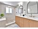 Beautifully renovated bathroom with double sink vanity, designer mirrors, and tiled shower with window at 6716 W Rowland Ave, Littleton, CO 80128