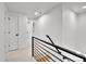 Bright hallway featuring white walls, doors, and modern black railings leading to the next level at 6716 W Rowland Ave, Littleton, CO 80128