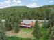 Aerial view of home showcasing its expansive deck, wood exterior, and peaceful treed surroundings at 28465 Cragmont Dr, Evergreen, CO 80439