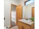 Bathroom with tiled countertop vanity, wood cabinets, mirror, and wood door at 28465 Cragmont Dr, Evergreen, CO 80439