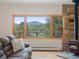 Inviting living room featuring a rustic stone fireplace and panoramic mountain view through large windows at 28465 Cragmont Dr, Evergreen, CO 80439