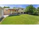 Spacious backyard showcasing a covered patio, a large green lawn, and mature trees at 980 S Nile Way, Aurora, CO 80012
