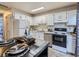 Well-lit kitchen featuring white cabinets, granite countertops, and stainless steel appliances, perfect for cooking at 17681 E Loyola Dr # E, Aurora, CO 80013