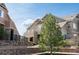 Exterior view of a tan home with stone accents, a tree in front and blue skies at 5732 S Addison Way # E, Aurora, CO 80016