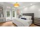 Cozy bedroom with decorative ceiling light, light wood floors, and backyard views at 96 Glenmoor Ln, Cherry Hills Village, CO 80113