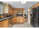 Kitchen featuring wood cabinets, granite countertops, stainless steel appliances, and view to office or dining area at 1758 S Tucson St, Aurora, CO 80012