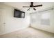 Comfortable bedroom with a mounted TV, ceiling fan, two windows, and carpet flooring at 9283 Sedalia St, Commerce City, CO 80022
