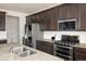 Modern kitchen with stainless steel appliances, dark cabinetry, and a granite countertop island at 9283 Sedalia St, Commerce City, CO 80022