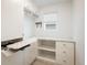 Well-lit laundry room with built-in ironing board, shelving, drawers, and a window for natural light at 9283 Sedalia St, Commerce City, CO 80022