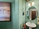 Stylish half bathroom with green walls, pedestal sink, round mirror, and decorative accents at 10273 Salida St, Commerce City, CO 80022