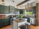 Charming kitchen featuring olive green cabinets, wooden ceiling beams and island with bar seating at 10273 Salida St, Commerce City, CO 80022