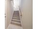 Carpeted stairs with wood railing leading upstairs at 17358 Waterhouse Cir # F, Parker, CO 80134