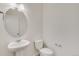 Simple bathroom with pedestal sink, toilet, and oval mirror at 2245 Base St, Fort Lupton, CO 80621