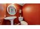 Stylish half bathroom features a modern sink, toilet, round mirror, and vibrant red walls at 8752 E Amherst Dr # D, Denver, CO 80231