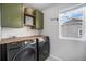 Laundry room with modern washer and dryer, wooden countertop, and storage cabinets at 1616 Metcalf Dr, Erie, CO 80516