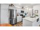 Well-lit kitchen featuring stainless steel refrigerator, white cabinets, and stylish countertops at 5231 S Greens Cir, Littleton, CO 80123