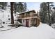 A unique home with a stylish deck, wood railings, and a snow-covered wooded setting at 11710 Spruce Canyon Cir, Golden, CO 80403