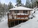 Charming home with a deck and railings, surrounded by snow-covered evergreens in a tranquil winter setting at 11710 Spruce Canyon Cir, Golden, CO 80403