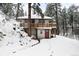 Cozy home nestled in a snowy, wooded landscape with a charming deck and unique wood railings at 11710 Spruce Canyon Cir, Golden, CO 80403