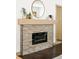 Modern fireplace with a stone surround, mantel, mirror, black electric firebox and dark hardwood floors at 11710 Spruce Canyon Cir, Golden, CO 80403